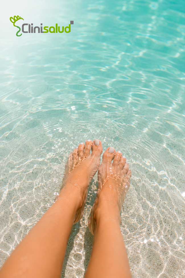Pies de mujer en el agua del mar — verano saludable con pies cuidados